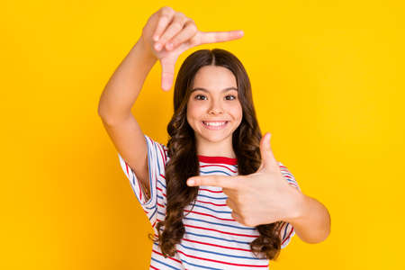 Photo of young beautiful positive smiling girl taking picture with fingers wear striped t-shirt...