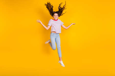Full length photo of young preteen girl happy positive smile have fun jump up isolated over yellow color backgroundの写真素材