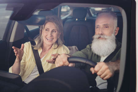 Portrait of attractive cheerful couple married spouses riding car having fun communicating spending...