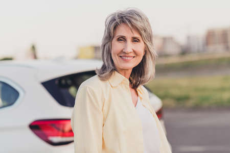 Photo of aged cheerful woman good mood trip urban road rent car transport vehicle ride weekend...
