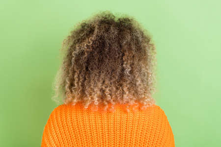 Back photo of millennial blond lady wear orange pullover isolated on green color backgroundの写真素材
