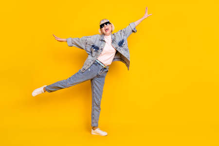Full length body size photo of senior woman wearing sunglass denim outfit careless isolated bright yellow color backgroundの写真素材