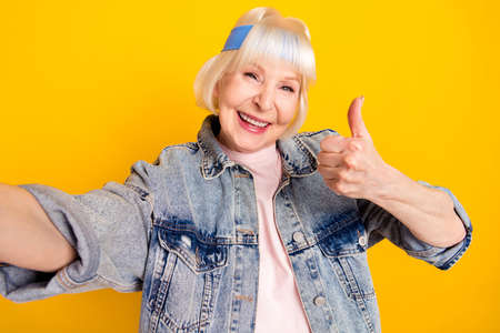 Self-portrait of elderly retired pensioner cheerful woman showing thumbup success isolated over...