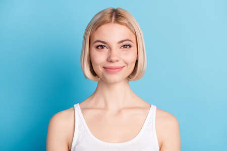 Close-up portrait of lovely cheerful blond girl wearing tanktop isolated over vivid blue color...