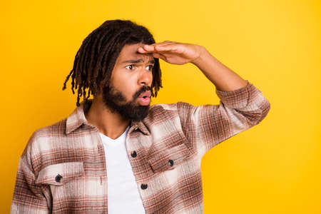 Photo portrait of bearded man looking far on blank space keeping hand on forehead whistle isolated on vibrant yellow color backgroundの写真素材