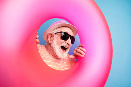 Photo of funky pretty mature man dressed yellow outfit headwear glasses looking pink swimming circle...