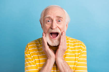 Close-up portrait of nice amazed cheerful gray-haired man good news reaction isolated over bright blue color backgroundの写真素材