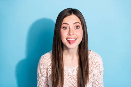 Photo of positive young funky woman stick out tongue make funny face isolated on pastel blue color...