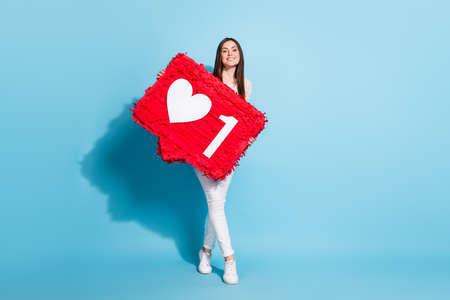 Full size photo of charming happy nice young woman smile hold like heart media icon isolated on blue...