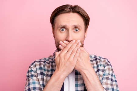 Photo of young man afraid worried nervous cover lips hands tell secret information isolated over pink color backgroundの写真素材