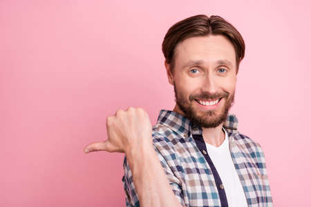 Photo of young cheerful man happy positive smile point thumb empty space ad suggest sale isolated...