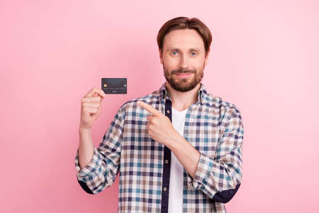 Photo of young man happy positive smile indicate finger credit card pay ad advice choice isolated...