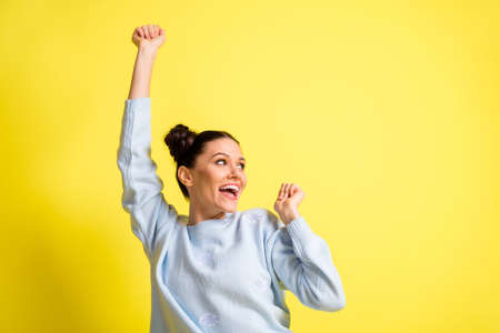 Photo of crazy lady dance raise hand have fun look empty space wear blue sweater isolated yellow backgroundの写真素材