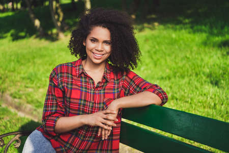 Photo portrait woman sitting on bench in city park in spring sunny weather spending free timeの写真素材