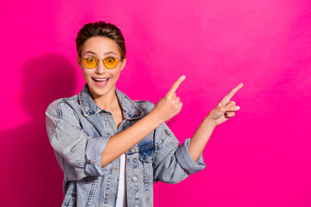 Photo of young amazed shocked woman point finger empty space good mood news isolated on pink color...