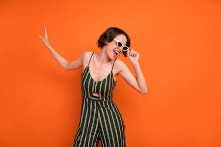Photo of young attractive girl happy positive smile hand touch glasses isolated over orange color...