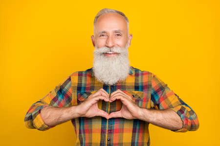 Photo of senior man show arms heart symbol cupid cardiac love romantic isolated over yellow color...