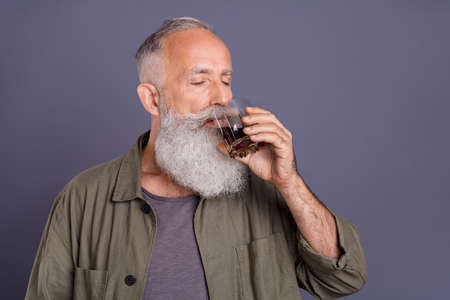 Photo of retired rich man enjoy drink delicious whiskey restaurant rest isolated over grey color backgroundの写真素材