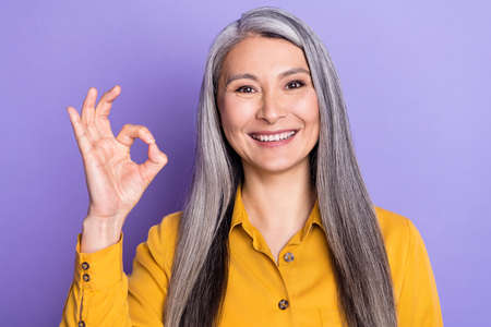 Portrait of attractive cheerful woman showing ok-sign ad advert isolated over bright violet purple...
