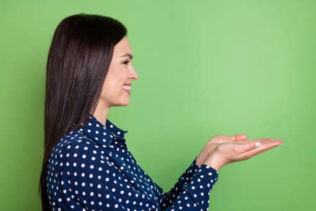 Profile photo of funky brunette hairdo sweet lady hold empty space wear blue shirt isolated on green color backgroundの写真素材