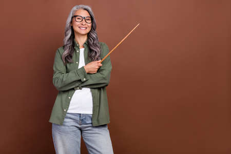 Photo of funny elder white hairdo lady index empty space wear shirt eyesight jeans isolated on brown color backgroundの写真素材