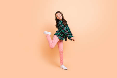 Photo of charming funky schoolgirl wear plaid outfit walking dancing smiling isolated beige color backgroundの写真素材
