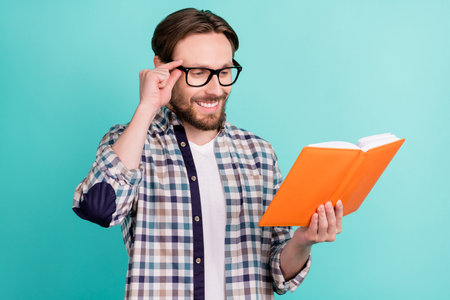 Profile side photo of young man happy positive smile read book materials education isolated over teal color backgroundの写真素材