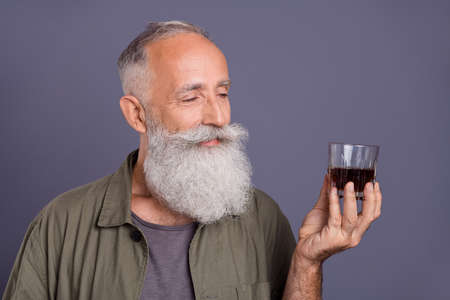 Photo of senior man degustate bourbon sommelier drink alcohol event isolated over grey color backgroundの写真素材