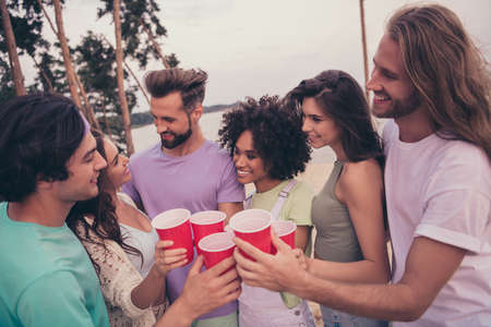 Portrait of attractive cheerful people meeting drinking beer celebrating having fun at beach wood...