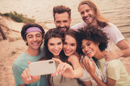 Photo of influencer blogger tourist buddies hold phone take selfie wear casual outfit nature seaside...