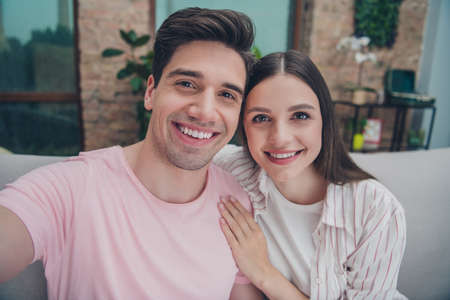 Self-portrait of attractive cheerful married spouses enjoying spending time daydream hugging pastime at home indoorsの写真素材