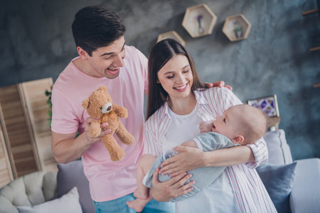 Portrait of attractive cheerful life partners rocking adopted cute baby resting good mood enjoying sweet time at home indoorsの写真素材