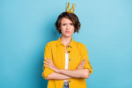 Photo of sad young brunette lady crossed hands wear yellow shirt crown isolated on blue color backgroundの写真素材