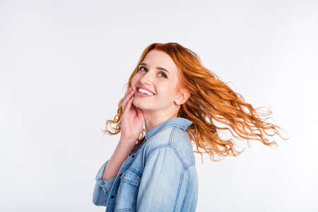 Photo of attractive young dream positive woman look empty space hold hand face fly hair isolated on grey color backgroundの写真素材