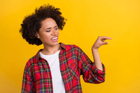 Portrait of attractive girl showing copy space pityful object isolated over bright yellow color backgroundの写真素材