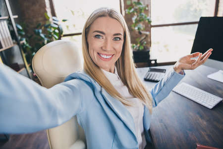 Photo of successful boss lady hr sit desk make selfie online present modern building workstation...