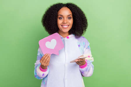 Photo of millennial lady use gadget hold heart icon check social network blog click isolated over green color backgroundの写真素材