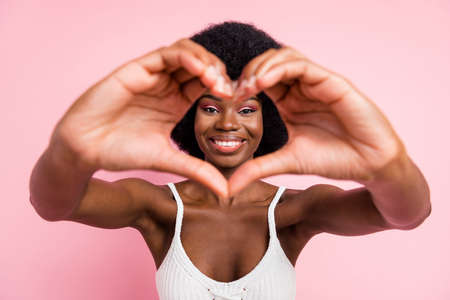 Photo of flirty young wavy hairdo lady show heart wear white top isolated on pastel pink color backgroundの写真素材