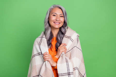 Photo of aged cheerful woman close herself blanket warm cozy enjoy isolated over green color...