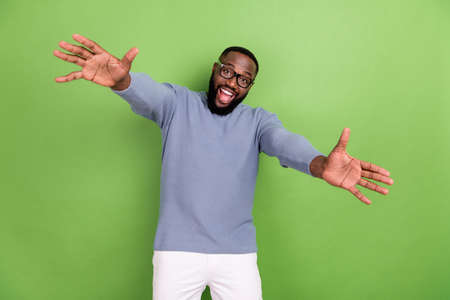 Photo of excited afro guy wear grey pullover arm glasses open arms want hug you isolated green color...