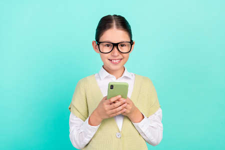 Photo of focused blogger small lady hold telephone post message wear green top isolated teal color...