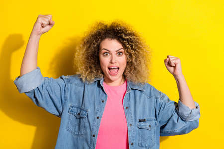 Photo of astonished lady raise fists celebrate lucky bet victory wear jeans shirt isolated yellow...