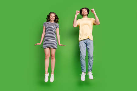 Full size photo of young couple happy positive smile have fun jump rejoice success isolated over green color backgroundの写真素材