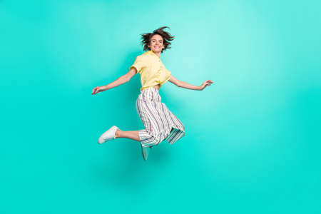 Full size profile side photo of young girl happy positive smile have fun jump up isolated over teal color backgroundの写真素材