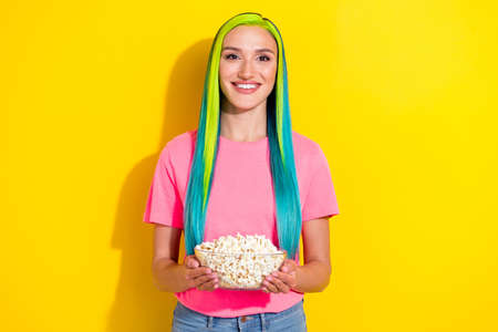 Portrait of attractive cheerful modern girl eating corn spending free spare time isolated over...