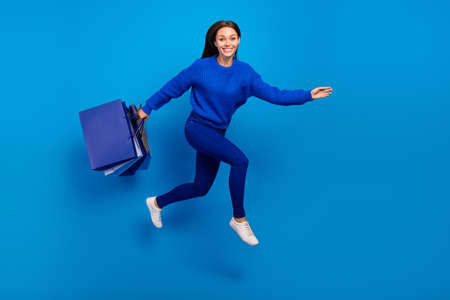 Full length body size view of attractive cheerful girl jumping carrying bags store outlet isolated...