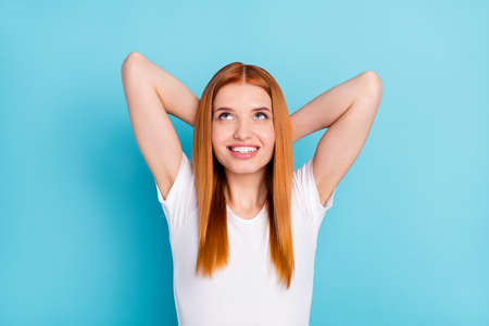 Photo of charming positive orange hair lady hands behind head look up empty space isolated on blue...