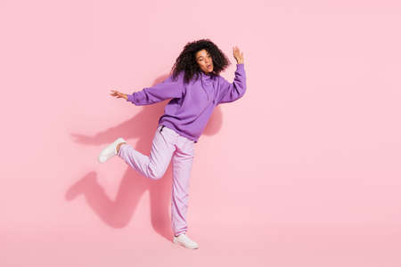 Photo of adorable pretty african lady dressed purple hoodie smiling dancing empty space isolated...