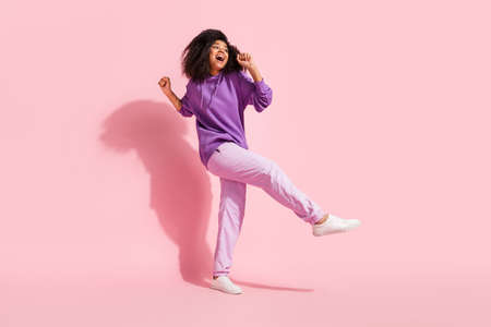 Photo of pretty shiny african lady dressed purple hoodie smiling dancing singing microphone isolated...