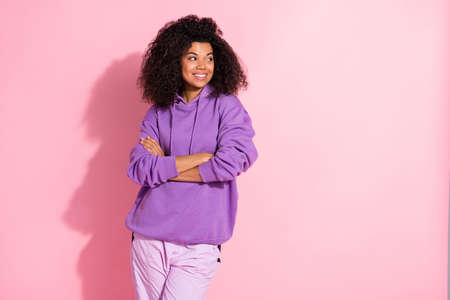 Photo of dreamy pretty afro girl wear violet sweatshirt arms crossed looking empty space smiling isolated pink color backgroundの写真素材